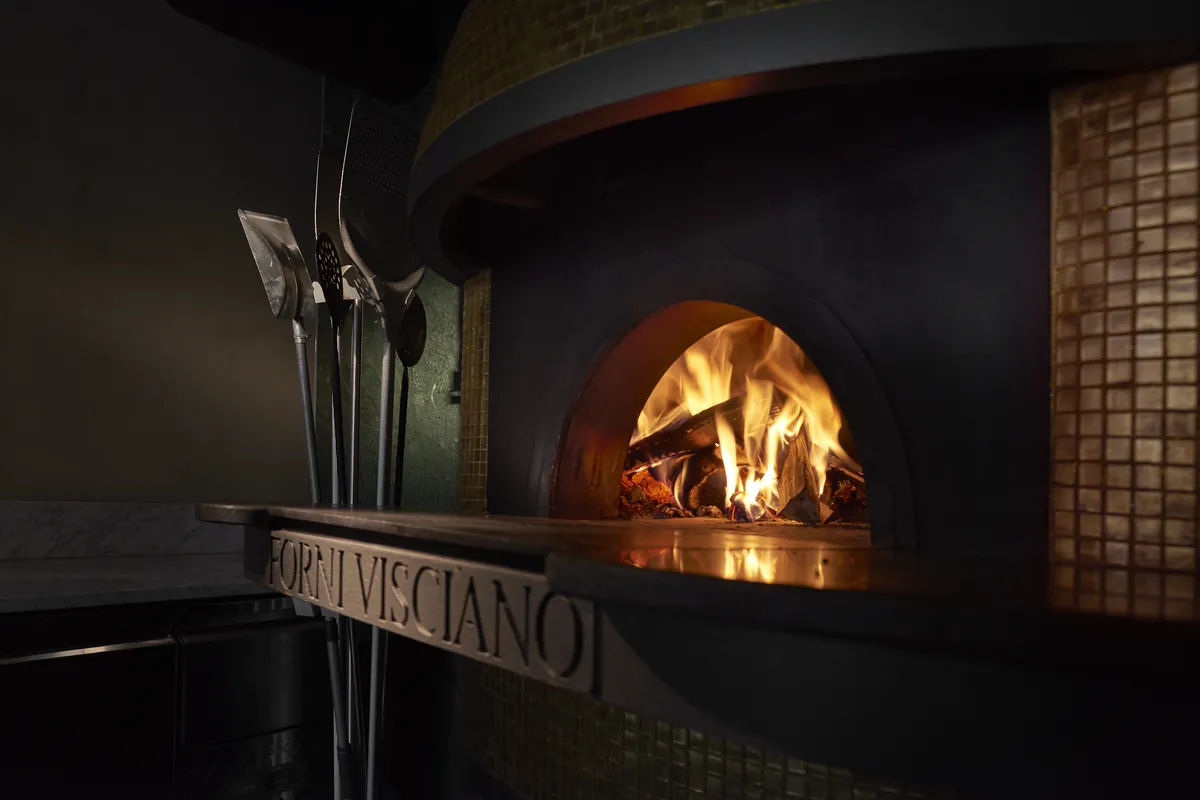 The oven from the side, peels hanging beside it