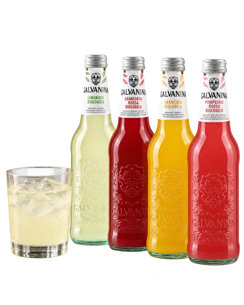 Four bottles of Galvanina beside a glass of lemonade