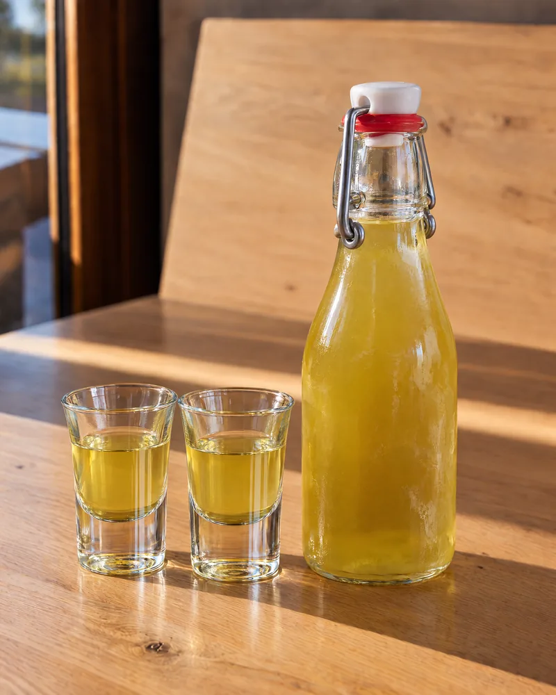 A bottle of limoncello beside two small glasses