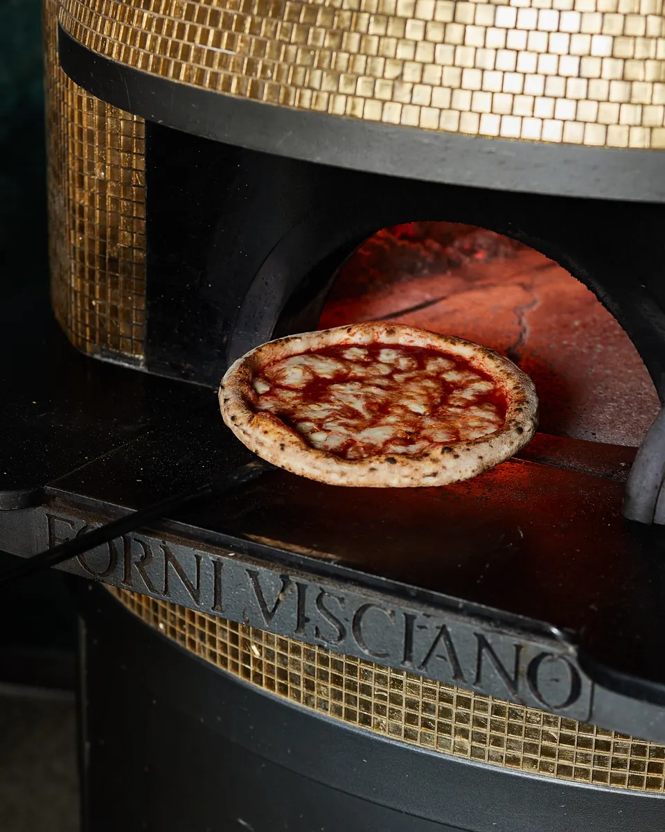 A Margherita on the peel in the wood-fired oven