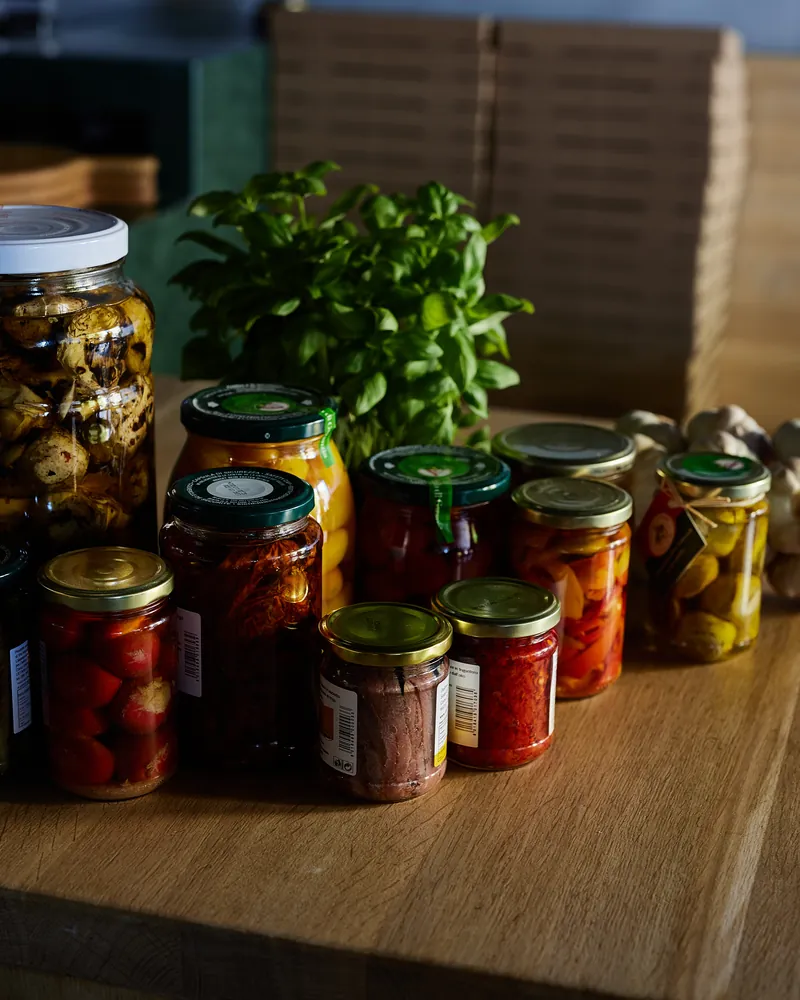 Jars of Italian preserves and fresh basil on the counter