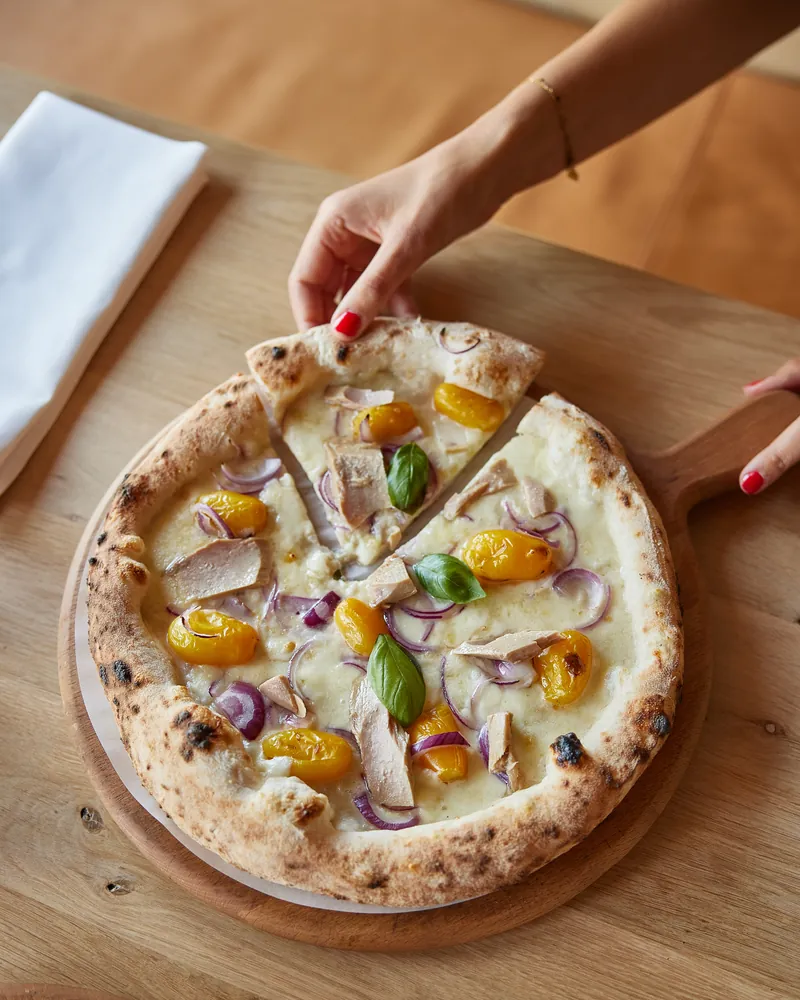 A hand taking a slice of pizza