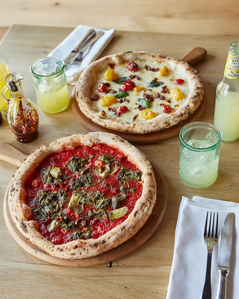 Two pizzas and drinks on a wooden table